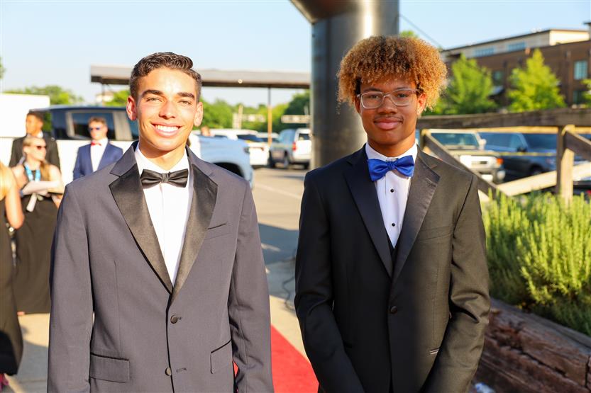 Two student-athletes wearing suits walk down the red carpet
